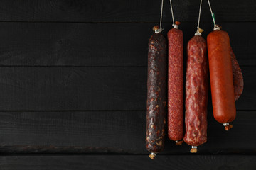 Delicious hanging sausages on wooden background, space for text