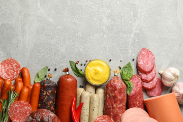 Different sausages and spices on grey background, space for text