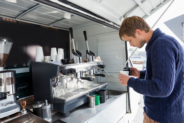 Profile shot of man pouring milk in cup at mobile coffee shop