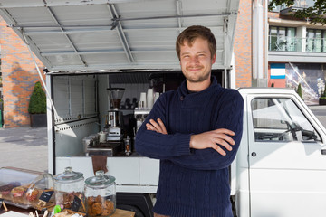Portrait of young man with arms crossed standing against mobile coffee shop