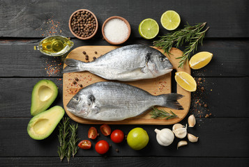 Cutting board with Dorado fishes and cooking ingredients on wooden background, top view Cutting board with Dorado fishes and cooking ingredients on wooden background, top view