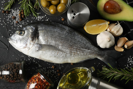 Fresh Dorado fish and cooking ingredients on black background, top view