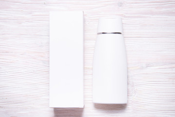 Top view, wthite cream bottle inside of carton cox, case on wooden backgrouns, copy space, mock up