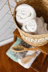 Fototapeta na wymiar Spa and bath cosmetics, basket with towel rolls in rustic interior. Natural materials in bathroom. Wooden hair brush. Bamboo comb on the dressing table. Eco-friendly hair care products. Natural beauty