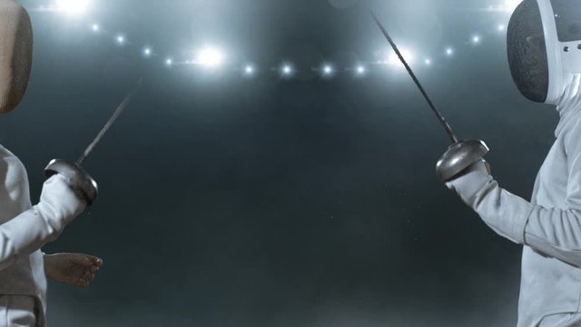Two fencing athletes fight on professional sports arena.