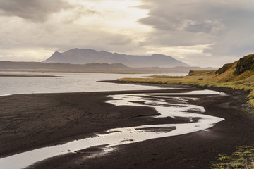 Dusk on the black sand beach before a mountain range on a gloomy day -- Iceland