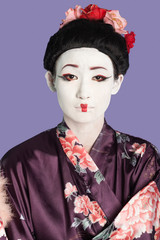 Portrait of Japanese woman in kimono with painted face against purple background