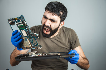 sad man repairing computer at table