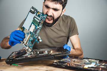 sad man repairing computer at table