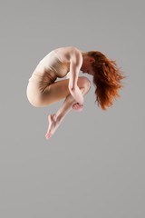 Dancer in mid-air with arms around knees