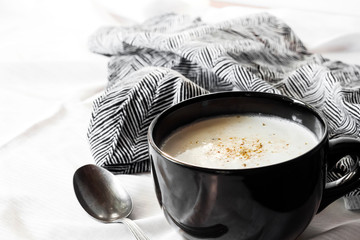 Cauliflower Soup (Creme du Barry) in black bowl on white background with black and white cloth.