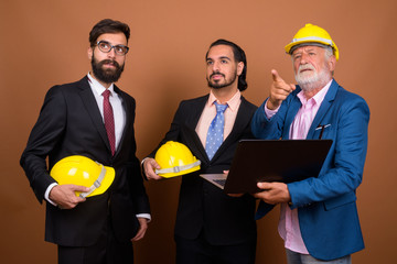 Three multi ethnic bearded businessmen together against brown background