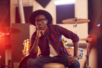 Portrait of contemporary African man looking at camera while posing in music recording studio