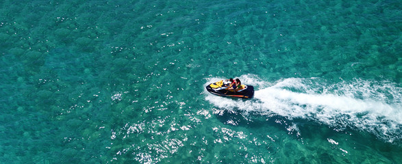 Aerial drone ultra wide photo of jet ski couple cruising in high speed in tropical exotic bay with...