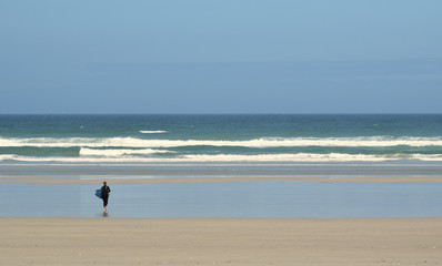 Fototapeta na wymiar Dans la baie d'Audierne dans le Finistère en Bretagne un surfeur s'apprête à affronter les vagues et à glisser sur leurs crêtes