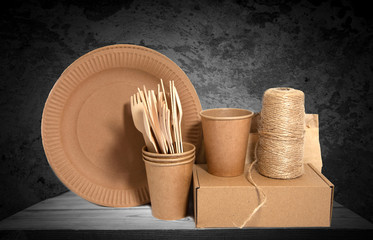 .Crockery made from eco kraft paper, paper cups, crockery, bag, fast food containers on a wooden, concrete wall background. Zero waste. Close-up.