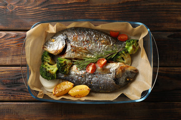 Grilled Dorado in baking tray on wooden background, top view