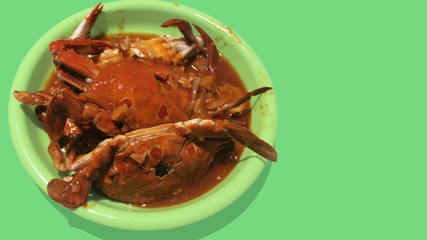 cooking tomato sauce crab on a green, homemade plate with a green background.