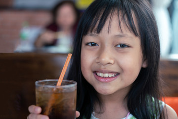 Asian children holding  and drinking cold drink in restaurant Unhealthy food and drink for Children concept