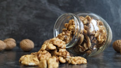 peeled walnut kernels in a glass jar for storing food on a light background