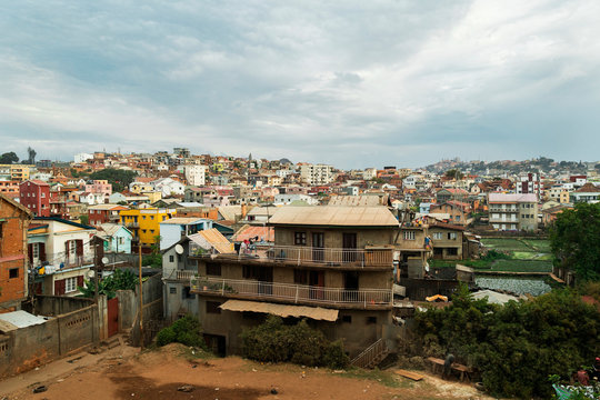 Antananarivo suburb with humble houses, colorful facades, rice fields and hills on cloudy day, Madagascar