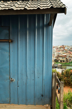 Blue colorful facade of humbre house in Antananarivo suburb surrounded by rice fields and hills on cloudy day, Madagascar