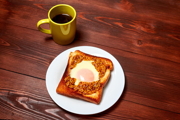 Toast with an egg and a cup of coffee on a dark wooden background.