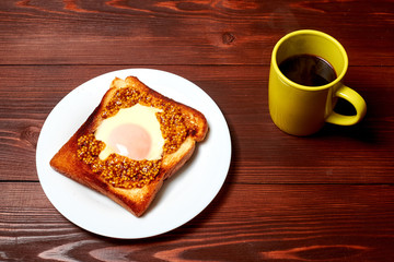 Toast with an egg and a cup of coffee on a dark wooden background.