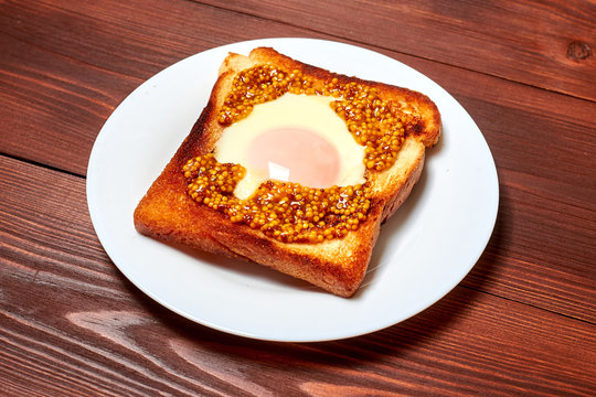 Toast with an egg on a plate on a dark wooden background.