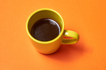 green cup with coffee on an orange background.