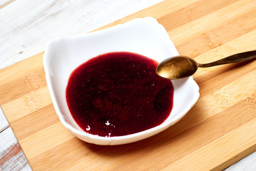 Strawberry jam on a light wooden background.