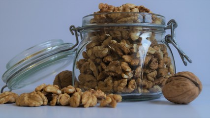 peeled walnut kernels in a glass jar for storing food on a light background
