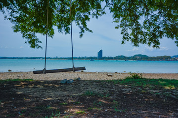 swing hanging on a tree by the sea,Tropical beach background as summer landscape with beach swing or hammock and white sand and calm sea for beach banner.