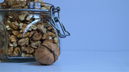 peeled walnut kernels in a glass jar for storing food on a light background