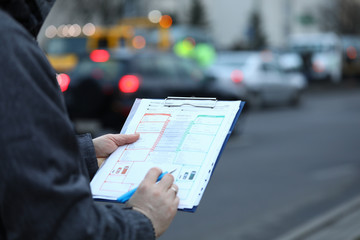 Close-up of male hands holding clipboard with documentations and writing down something. Accident...