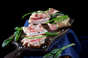 Salted pig fat on the wooden board. Ukrainian cuisine appetizer against the black background