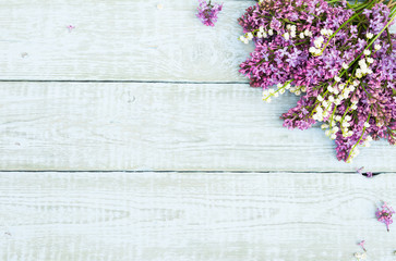 Bouquet of purple lilac flowers and Lily of the valley on a shabby wooden background. Vintage floral background with spring flowers. Copy space