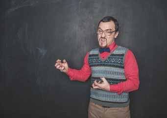 Angry teacher or business man on blackboard background