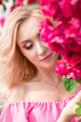 beautiful portrait of a blonde girl in pink roses. close-up, makeup, extended eyelashes