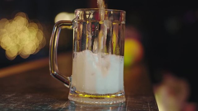 Closeup to the camera in a slow motion cold beer pouring into a glass of beer make bubbles