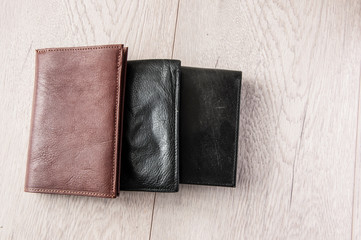 Three leather wallets on wooden table