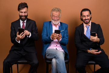 Three multi ethnic bearded businessmen together against brown background