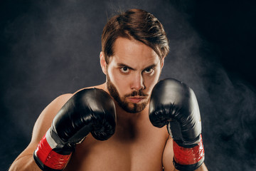 Fototapeta na wymiar shirtless boxer with gloves on dark background in smoke