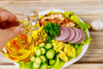 Woman holds olive oil for vegetable salad.