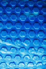 Abstract texture of a blue massage roller in the form of blue hexagonal cells. The entire screen as the background.