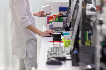Pharmacist holding medicine box and capsule pack in pharmacy drugstore.