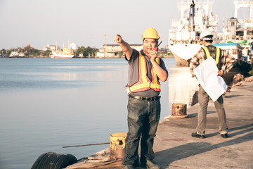 Portrait images of Engineers, technicians Asian, Standing on the marina And currently using radio...
