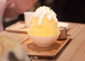 Korean shaved ice or snow cone (bingsu, bingsoo) dessert with chopped fresh tropical mango fruit, condensed milk, fruit syrup sweet toppings. Traditional Asian Snacks, Sweets, Treats and Food concept