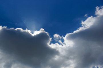 rays of the sun from behind storm clouds in the blue sky