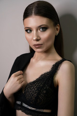 Beautiful young white girl close-up in a black jacket on a gray background. Make-up artist, beauty salon, stylist, magazine